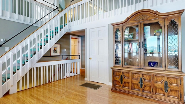 staircase with hardwood / wood-style floors and a towering ceiling