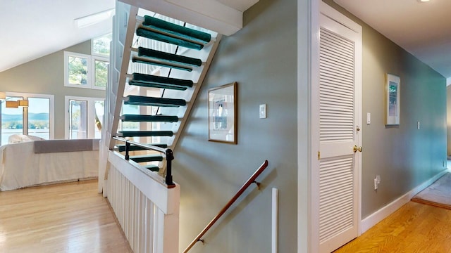 stairs featuring wood-type flooring and lofted ceiling