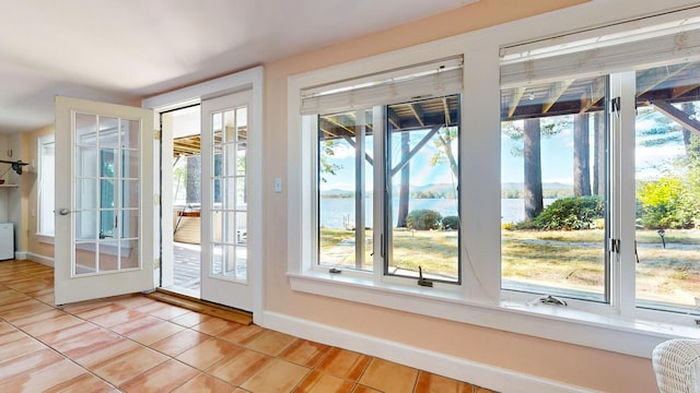 doorway to outside featuring light tile patterned floors and a water view