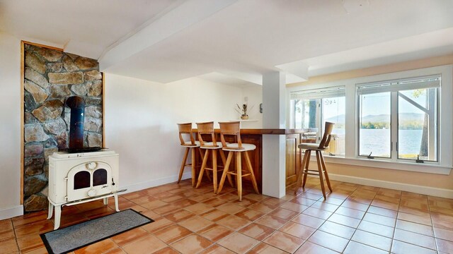 interior space featuring bar area, a wood stove, and light tile patterned floors