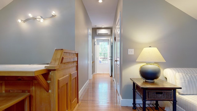 hall with light hardwood / wood-style floors and a wall unit AC