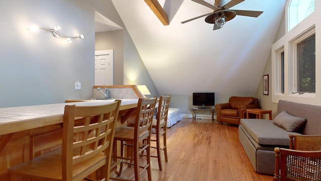 dining area featuring ceiling fan, light wood-type flooring, lofted ceiling, and sink