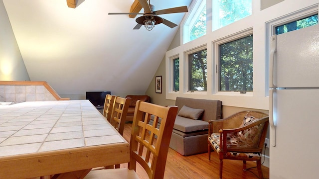 bedroom featuring white refrigerator, light hardwood / wood-style flooring, ceiling fan, and vaulted ceiling