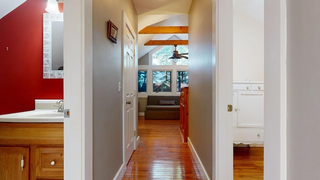 hallway featuring hardwood / wood-style flooring, lofted ceiling with beams, and sink