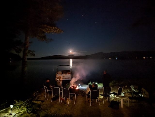 patio at night featuring a water view