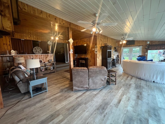 living room featuring hardwood / wood-style flooring, wood walls, vaulted ceiling, ceiling fan, and wooden ceiling