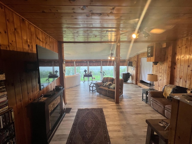 living room with wood ceiling, wood walls, light hardwood / wood-style floors, and ceiling fan