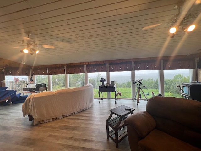 sunroom featuring ceiling fan, a wood stove, and wooden ceiling