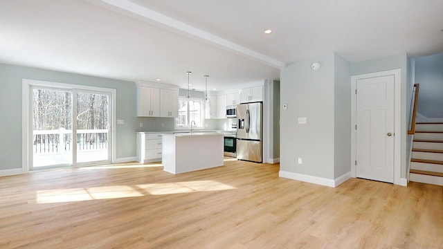 kitchen featuring pendant lighting, white cabinets, a center island, light hardwood / wood-style floors, and stainless steel appliances