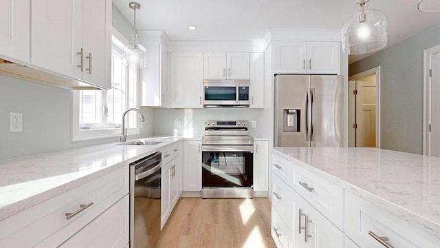 kitchen with stainless steel appliances, sink, pendant lighting, and white cabinets