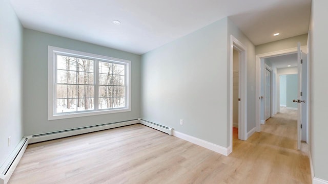 unfurnished room featuring a baseboard radiator and light hardwood / wood-style flooring