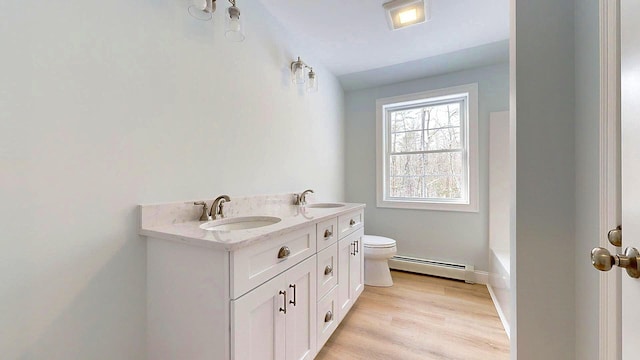 bathroom with vanity, hardwood / wood-style floors, baseboard heating, and toilet