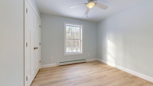 empty room featuring baseboard heating, ceiling fan, and light wood-type flooring