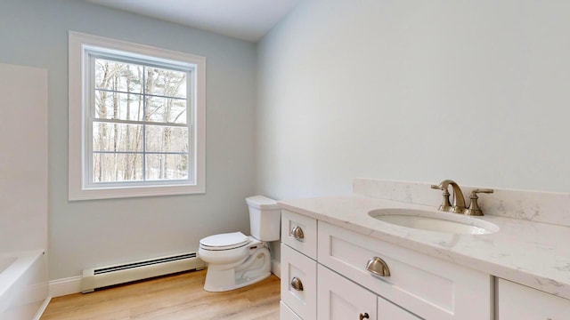 bathroom featuring a baseboard radiator, a bathtub, hardwood / wood-style flooring, vanity, and toilet