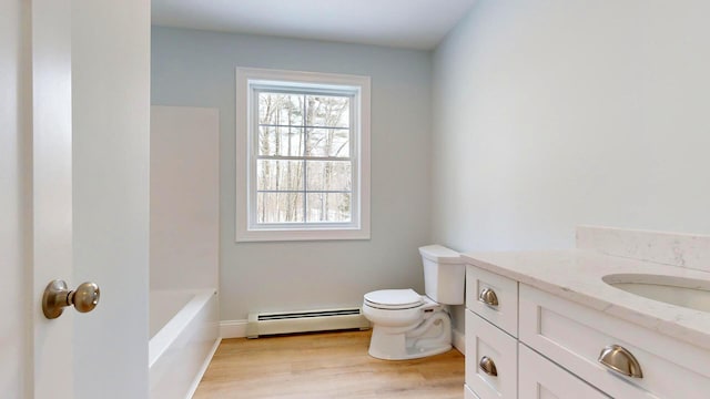 bathroom with toilet, vanity, a tub, hardwood / wood-style flooring, and a baseboard heating unit