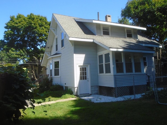 rear view of property featuring a sunroom and a yard