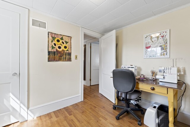 office area with light wood-type flooring and ornamental molding