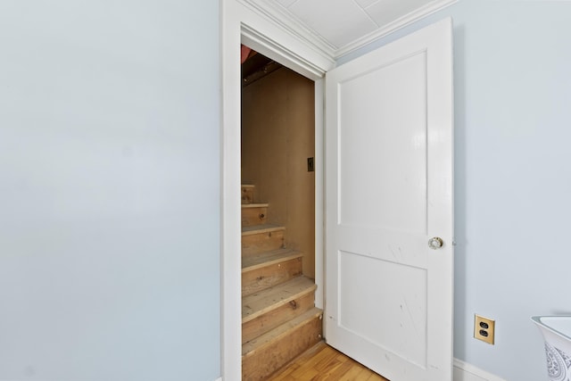 staircase with wood-type flooring and crown molding