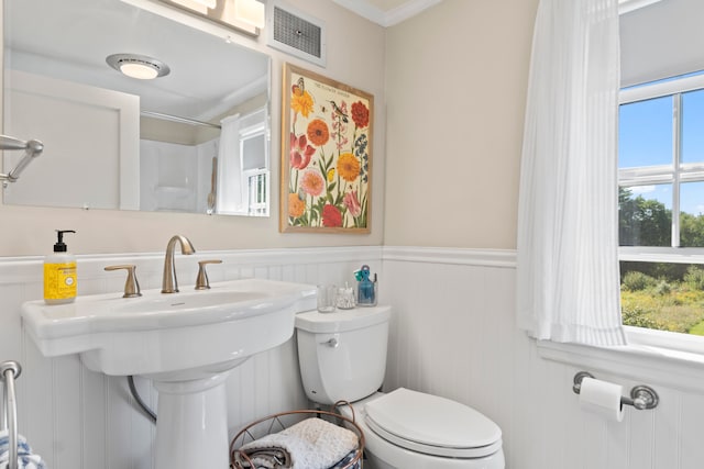 bathroom featuring a shower, toilet, and ornamental molding