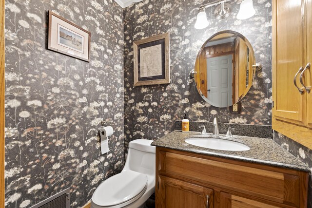 bathroom with toilet, crown molding, and vanity