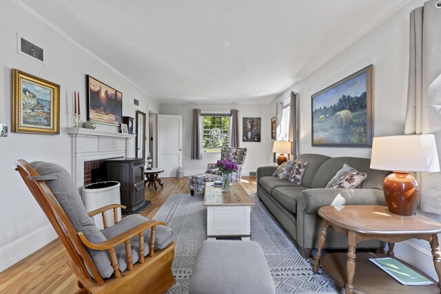 living room with light hardwood / wood-style flooring, ornamental molding, and a fireplace