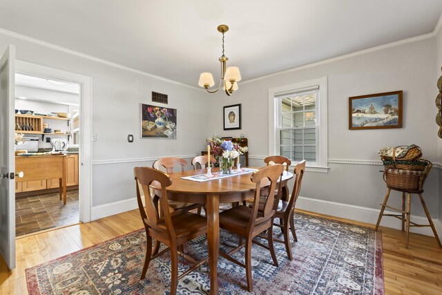 dining room featuring a chandelier, light hardwood / wood-style floors, and crown molding