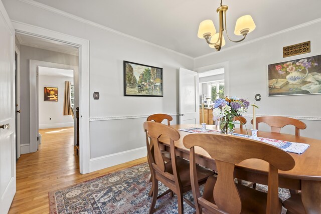 dining area with light hardwood / wood-style flooring, ornamental molding, and a chandelier