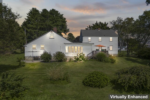 back house at dusk featuring a yard