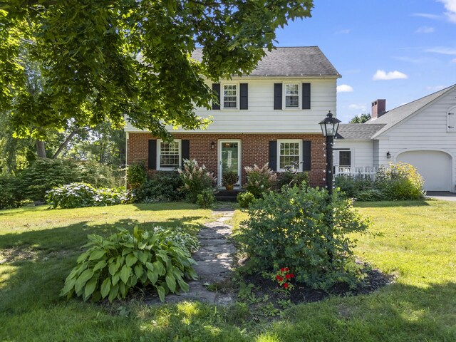 colonial house featuring a front yard and a garage