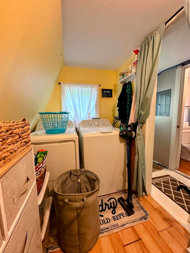 bathroom featuring hardwood / wood-style flooring, electric panel, vaulted ceiling, and washing machine and clothes dryer