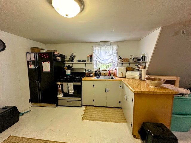 kitchen featuring black fridge, stainless steel range with gas cooktop, sink, light colored carpet, and butcher block countertops