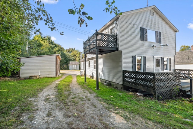 rear view of house with a wooden deck and a storage unit