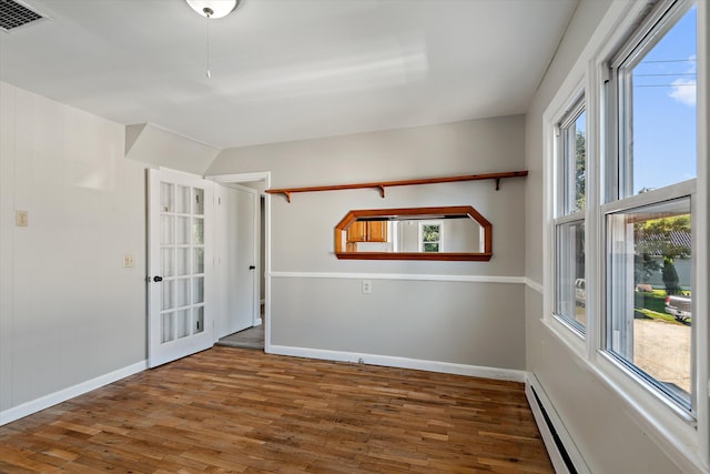 unfurnished room featuring dark wood-type flooring and a baseboard radiator