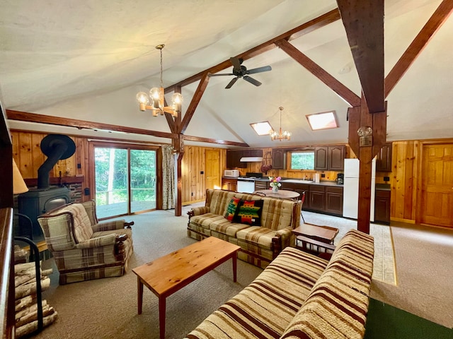 carpeted living room with high vaulted ceiling, ceiling fan with notable chandelier, wood walls, beamed ceiling, and a wood stove