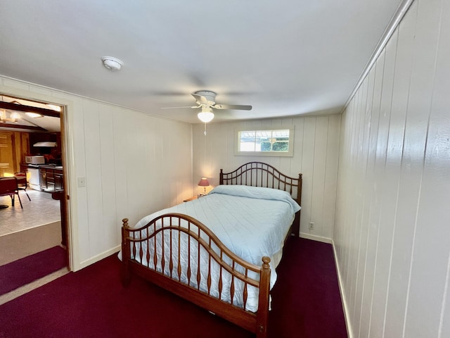 bedroom with wood walls, dark carpet, and ceiling fan