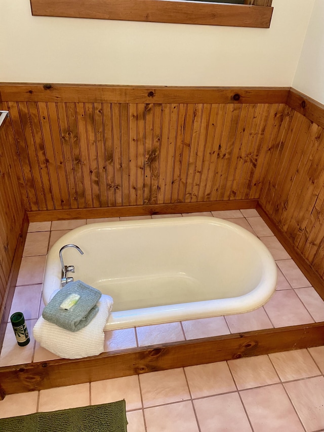 bathroom with wooden walls, a washtub, and tile patterned floors