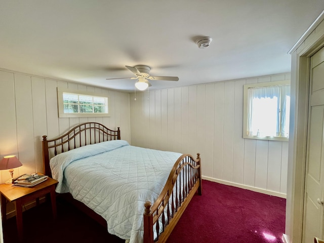 carpeted bedroom with ceiling fan and wooden walls