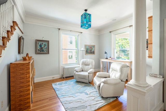 sitting room with ornate columns, ornamental molding, radiator, and light wood-type flooring