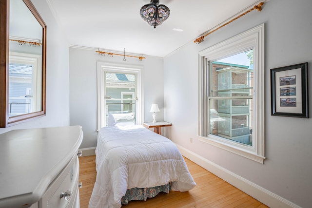 bedroom with crown molding, multiple windows, and light hardwood / wood-style floors