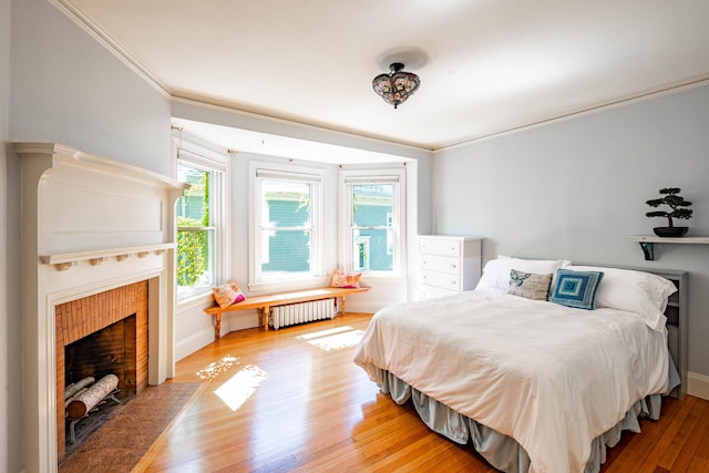 bedroom with crown molding, radiator heating unit, and hardwood / wood-style flooring