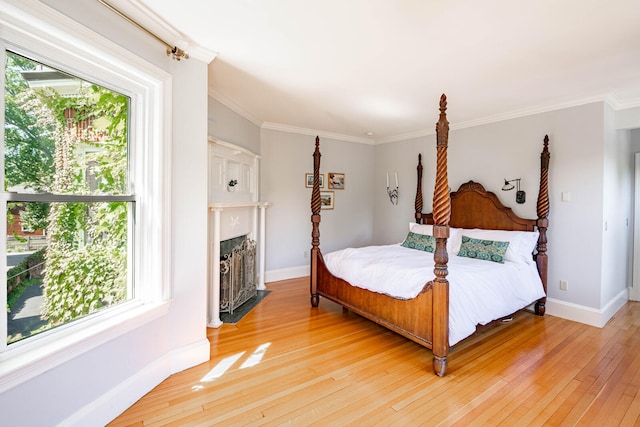 bedroom featuring ornamental molding, multiple windows, a fireplace, and hardwood / wood-style floors