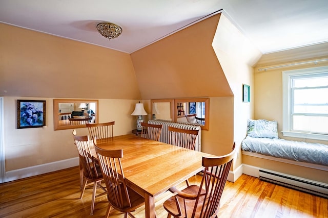 dining room with lofted ceiling, a baseboard heating unit, and hardwood / wood-style flooring