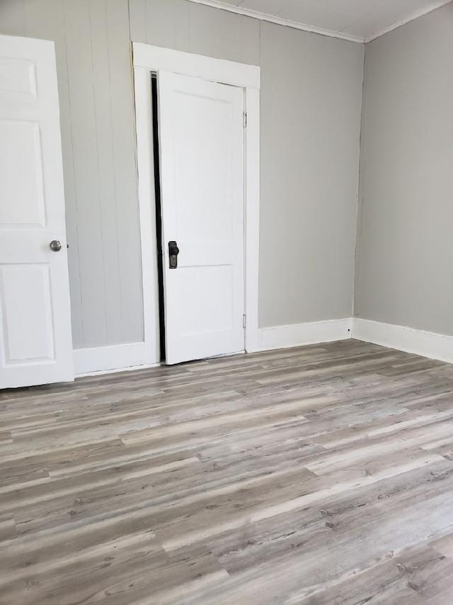 empty room with light wood-type flooring and crown molding