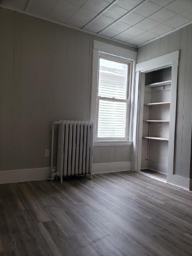 spare room with dark wood-type flooring and radiator heating unit