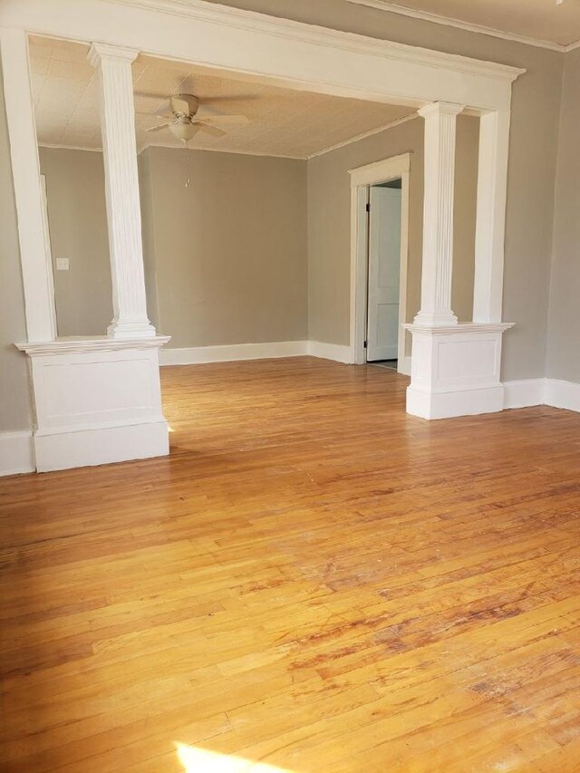 empty room with light hardwood / wood-style floors, ceiling fan, and ornate columns