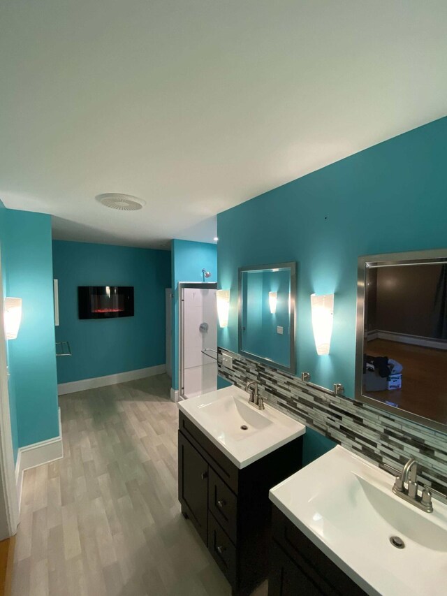 bathroom featuring wood-type flooring, decorative backsplash, and vanity