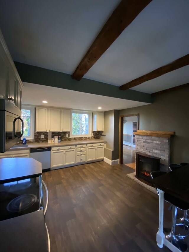 kitchen featuring backsplash, stainless steel appliances, dark hardwood / wood-style flooring, white cabinetry, and a stone fireplace