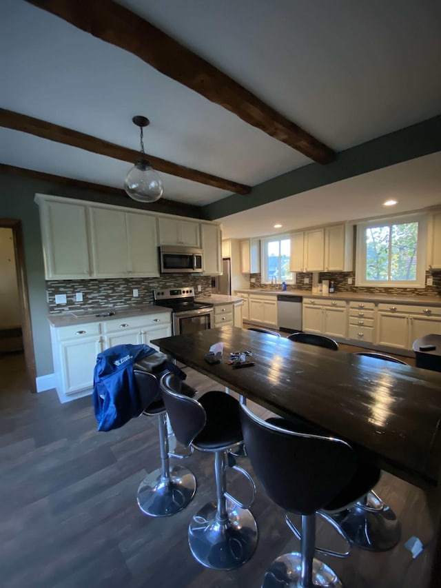 kitchen with stainless steel appliances, dark wood finished floors, beam ceiling, tasteful backsplash, and white cabinetry