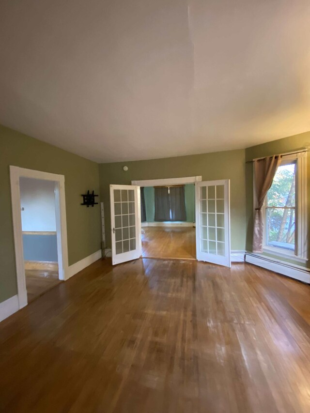 unfurnished living room featuring baseboard heating and hardwood / wood-style floors