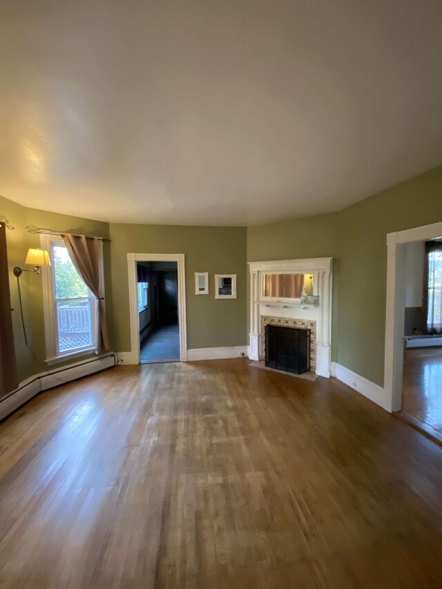 unfurnished living room featuring a baseboard heating unit and hardwood / wood-style floors